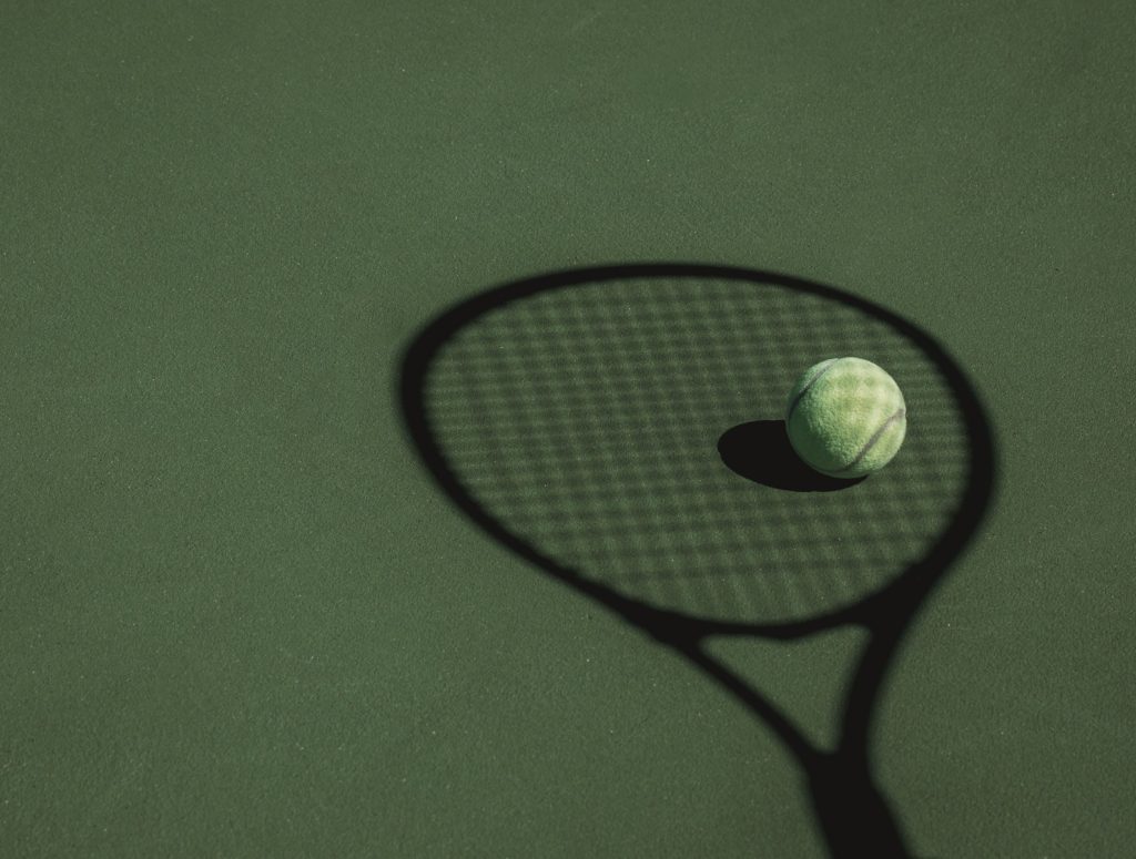 tennis-ball-sits-in-the-shadow-cast-by-a-tennis-racket